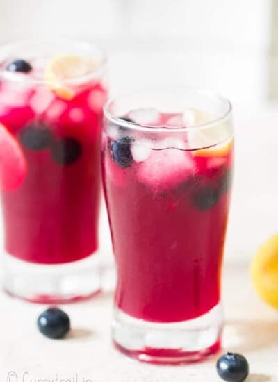 blueberry lemonade with lemon wedges served in two glasses