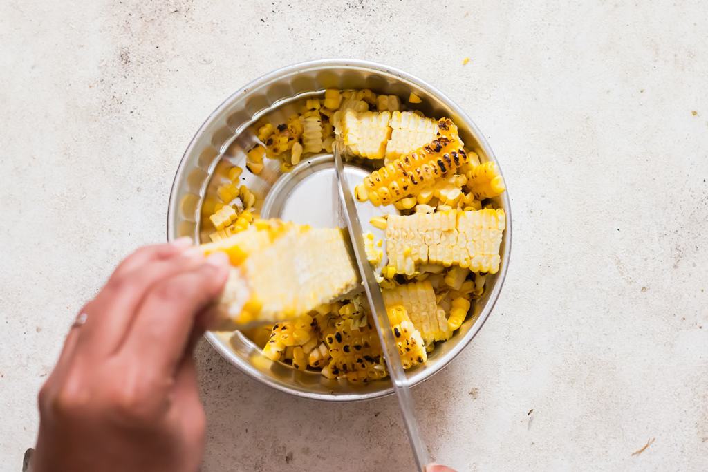 cutting grilled corn kernels from sweet corn.