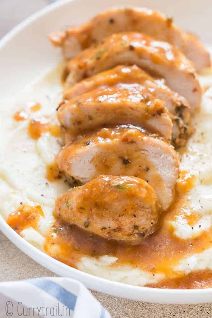 juicy moist chicken breasts cooked in instant pot served on top of mashed potatoes in white plate