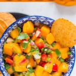 all ingredients for mango salsa in a bowl with nachos chip.