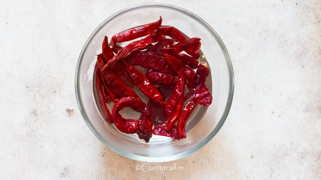 soak dried red chili peppers in water in a bowl.