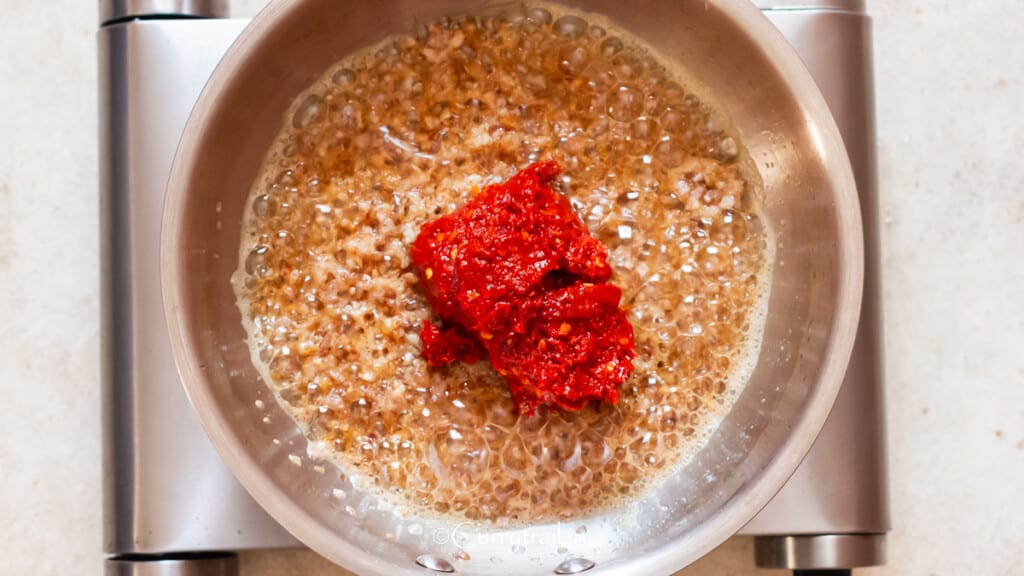 add ground red chili paste to the skillet.