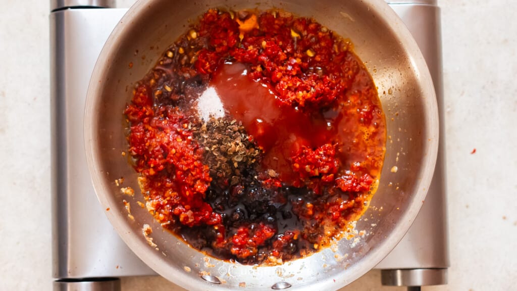 cooking schezwan sauce with vinegar, soy sauce, sugar, and schezwan pepper corn.