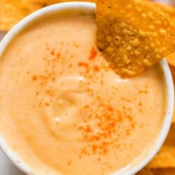 spicy nacho cheddar cheese sauce in small bowl with nachos on side