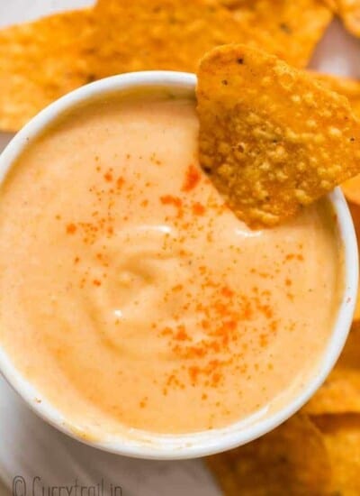 spicy nacho cheddar cheese sauce in small bowl with nachos on side