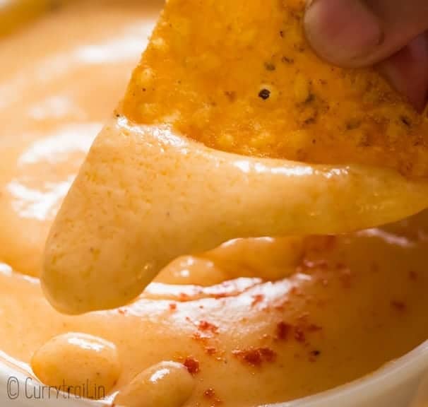 nacho dipped in spicy cheese sauce