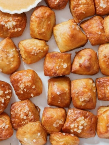 pretzel bites with a soft texture served with cheese dipping sauce on a plate.