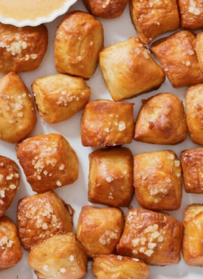 pretzel bites with a soft texture served with cheese dipping sauce on a plate.