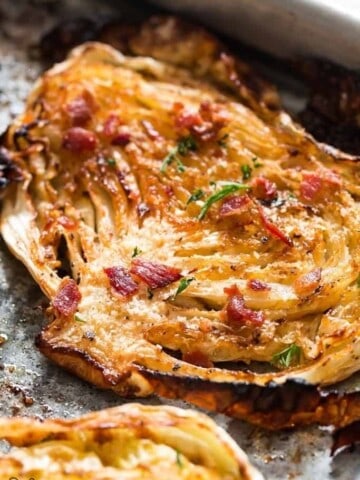 Cabbage steaks roasted in oven and garnished with Parmesan and bacon on baking tray