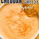 cheddar cheese sauce served in small bowl with nachos with text overlay