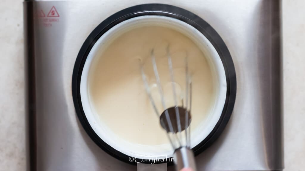 milk is added to flour mix in a saucepan to make the cheese sauce.