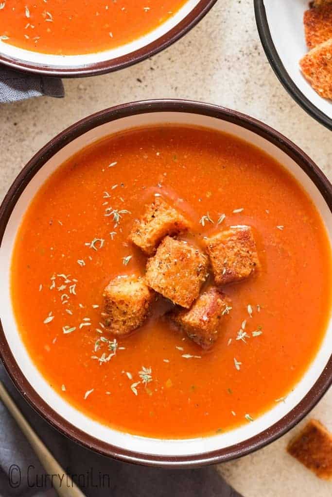 tomato basil soup in bowl served with croutons in bowls