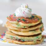 birthday cake pancakes on white plate with whipped cream and sprinkles