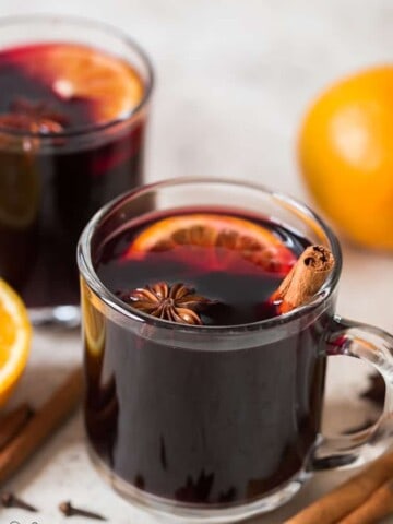 traditional mulled wine in heat proof mugs with spices on sides