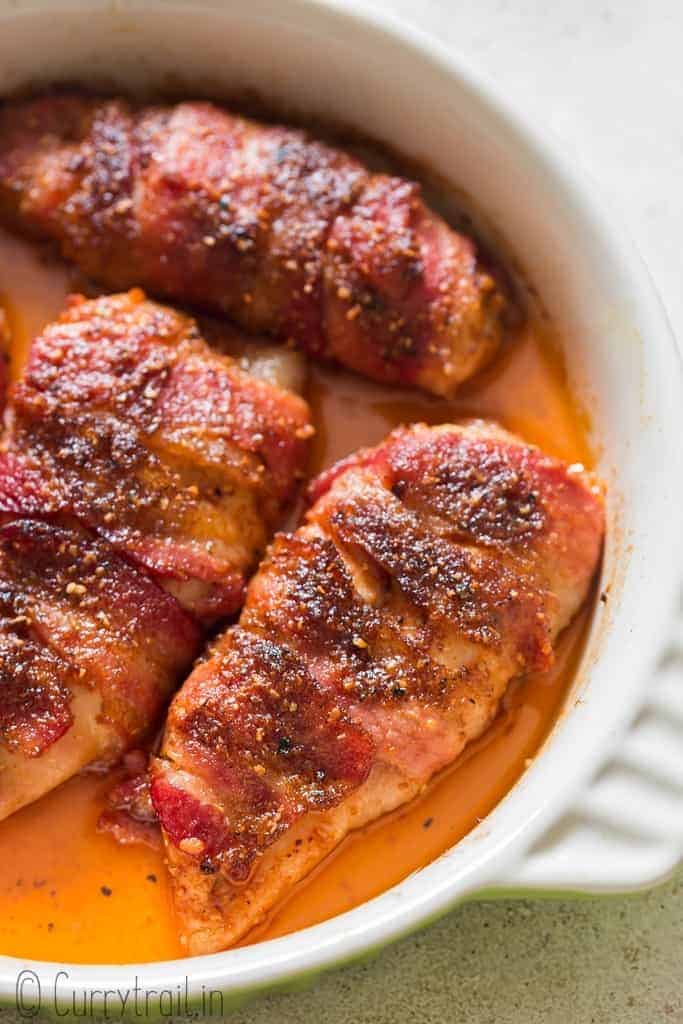 baked bacon wrapped chicken breast in baking dish.