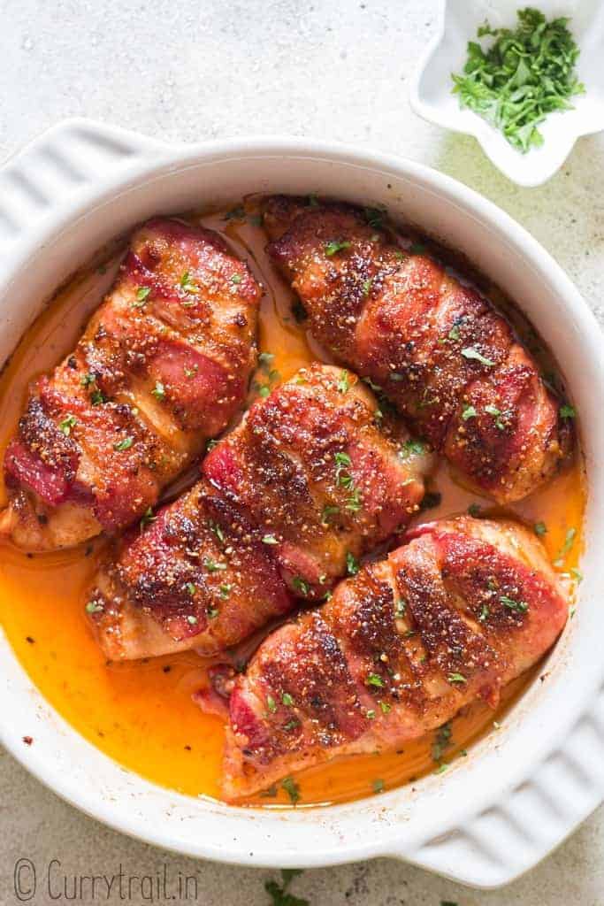 baked bacon wrapped chicken breast in baking dish with parsley garnish