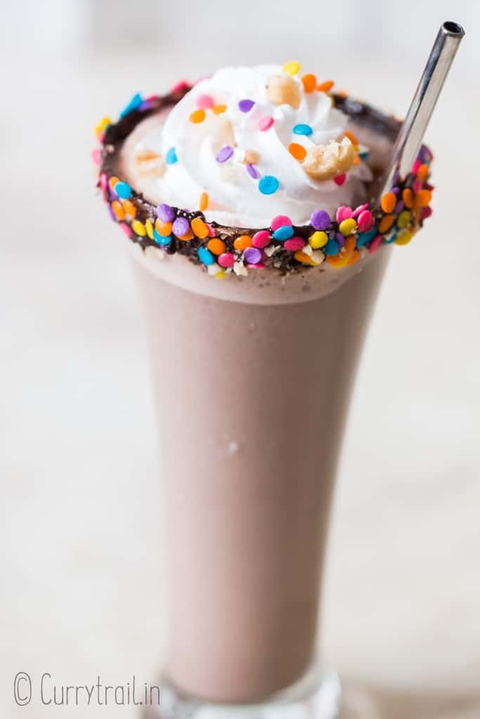 3 ingredients nutella milkshake in tall glass with whipped cream and straw