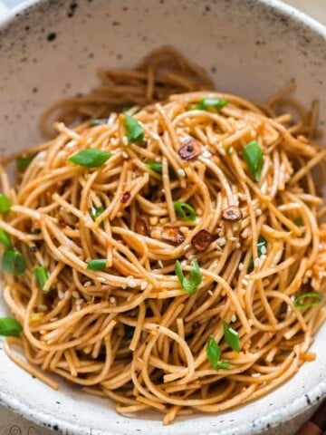 chili butter garlic noodles in white ceramic bowl with chopsticks on side