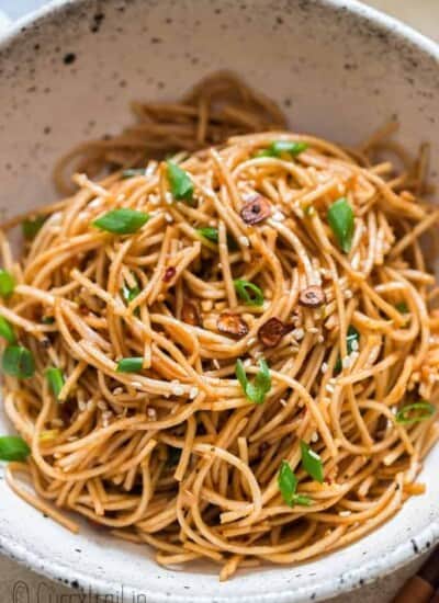 chili butter garlic noodles in white ceramic bowl with chopsticks on side