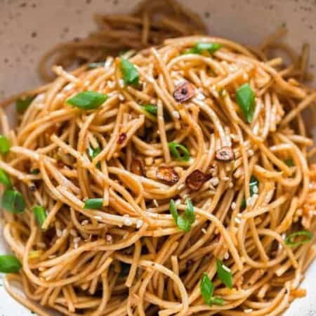 chili butter garlic noodles in white ceramic bowl with chopsticks on side