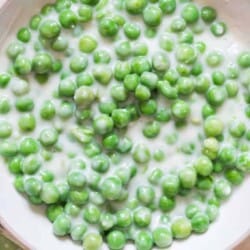 peas in white cream sauce in white ceramic bowl