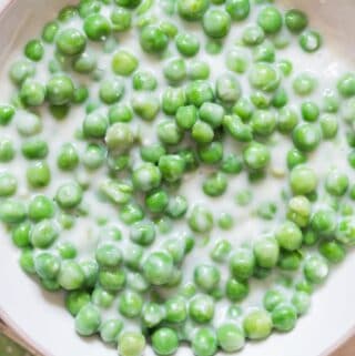 peas in white cream sauce in white ceramic bowl