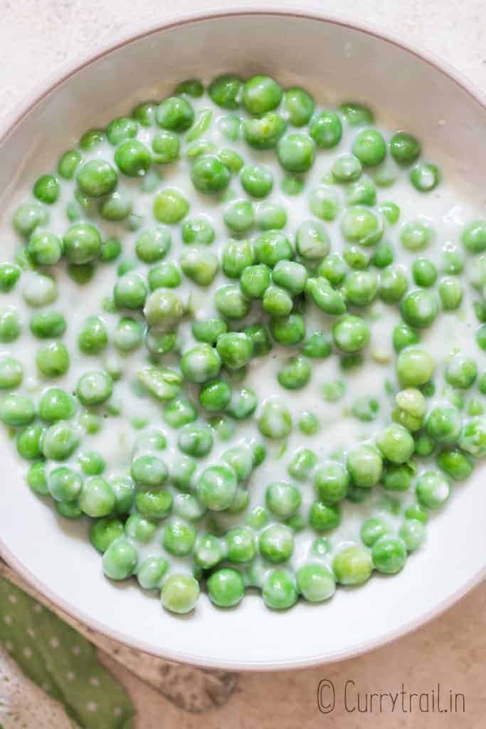 peas in white cream sauce in white ceramic bowl 