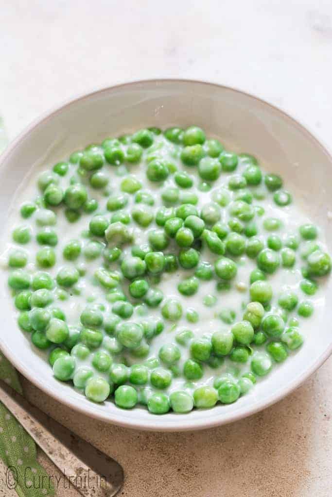 peas in white cream sauce in white ceramic bowl