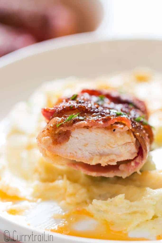 juicy chicken breast wrapped in bacon over mashed potato