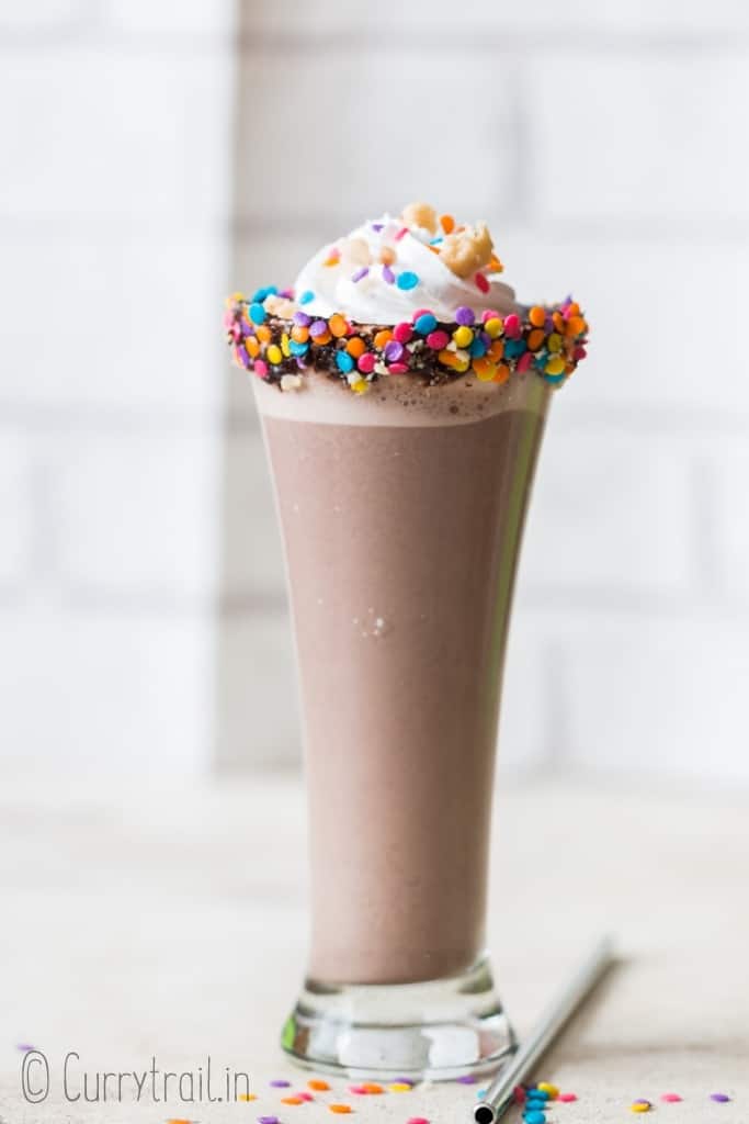 Nutella milkshake in tall glass with whipped cream and sprinkles