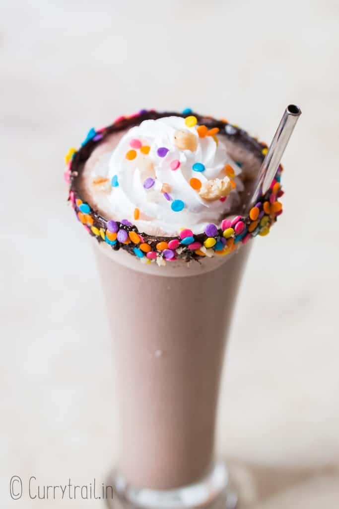 3 ingredients nutella milkshake in tall glass with whipped cream and straw