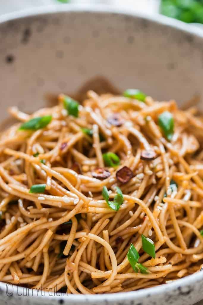 chili butter garlic noodles in white ceramic bowl with chopsticks on side