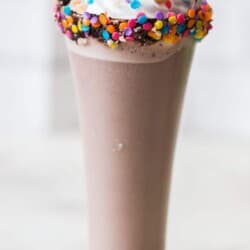 3 ingredients nutella milkshake in tall glass with whipped cream and straw