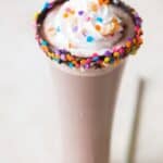 Nutella milkshake in tall glass with whipped cream and sprinkles with text