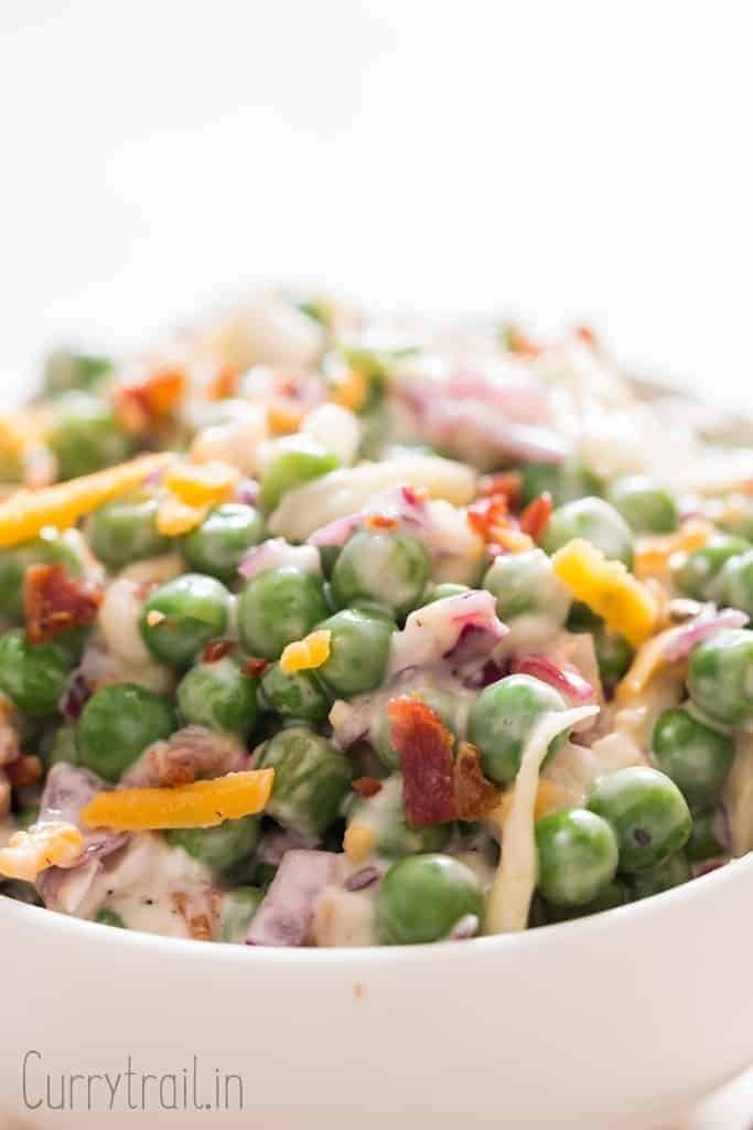 pea salad with cheese, bacon and red onion in ceramic bowl