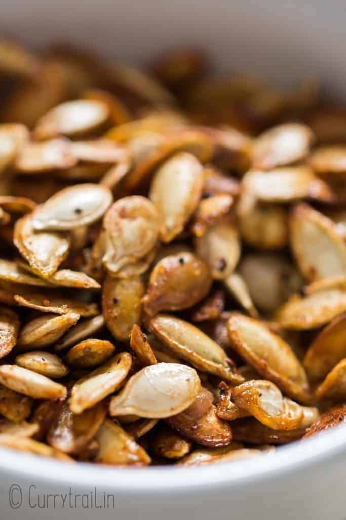 close up photo of savory roasted pumpkin seeds in ceramic bowl