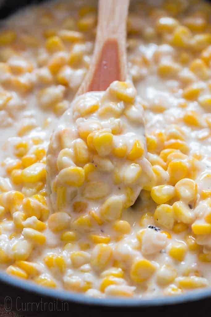 corn cooked in cream sauce in skillet with wooden spatula