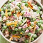 pea salad with cheese, bacon and red onion in ceramic bowl