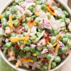 pea salad with cheese, bacon and red onion in ceramic bowl