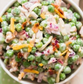 pea salad with cheese, bacon and red onion in ceramic bowl