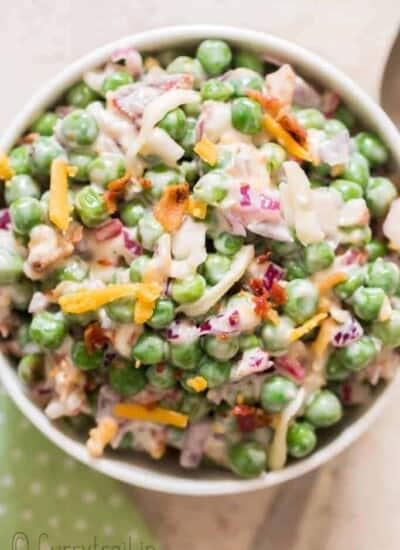 pea salad with cheese, bacon and red onion in ceramic bowl