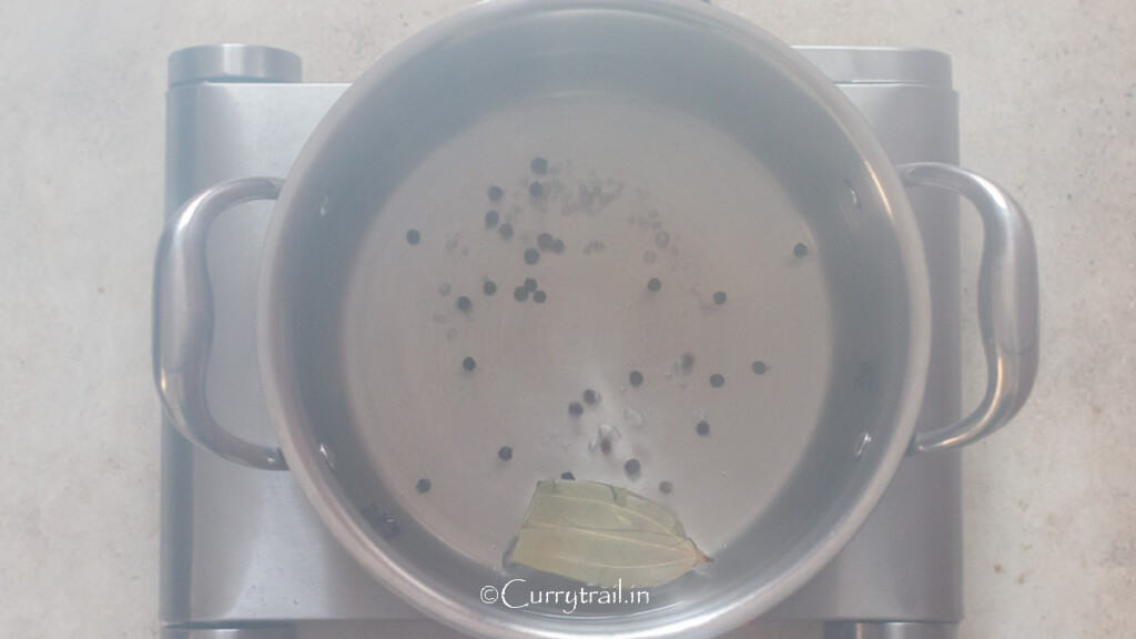 boiling water seasoned with salt, peppercorns, and bay leaf in a large pot.