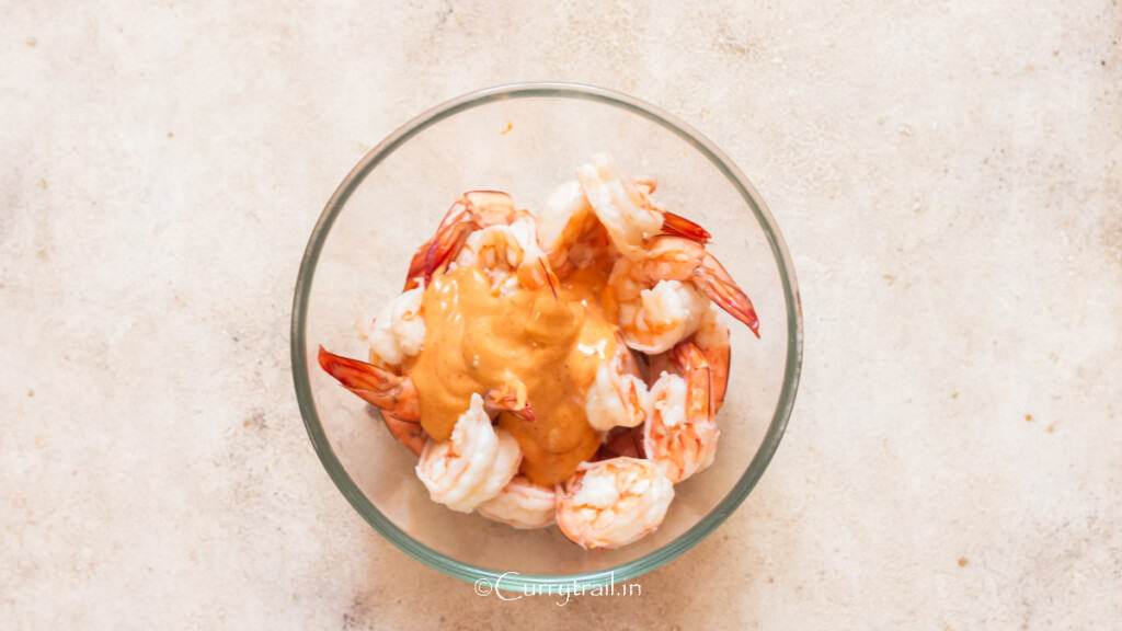 Marie Rose sauce is added to blanched prawns in a bowl.