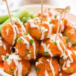 buffalo chicken meatballs stacked up on plate with blue cheese dressing on side