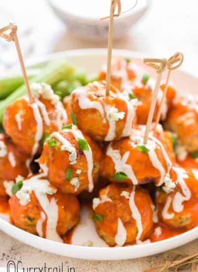 buffalo chicken meatballs stacked up on plate with blue cheese dressing on side