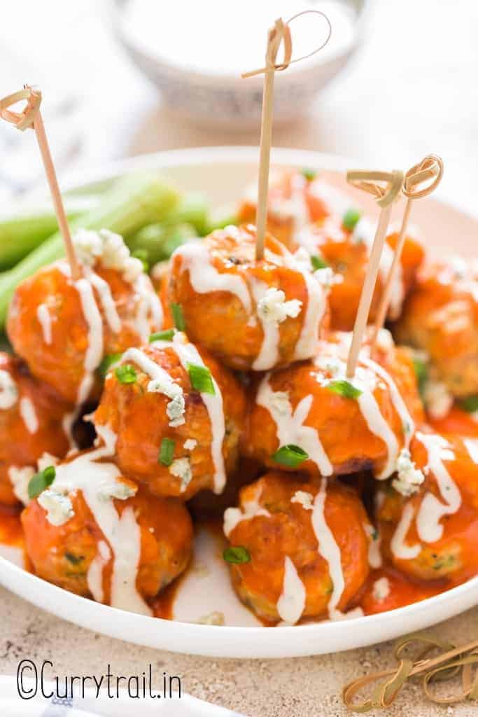 buffalo chicken meatballs stacked up on plate with blue cheese dressing on side