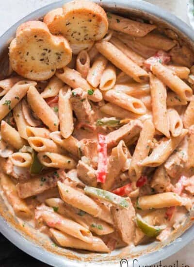 chicken pasta with cajun seasoning in cream sauce served in skillet with bread on sides