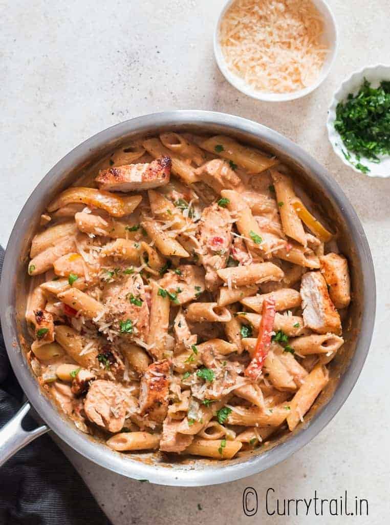 chicken pasta with cajun seasoning in cream sauce served in skillet with bread on sides