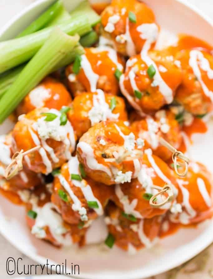 buffalo chicken meatballs stacked up on plate with blue cheese dressing on side with text