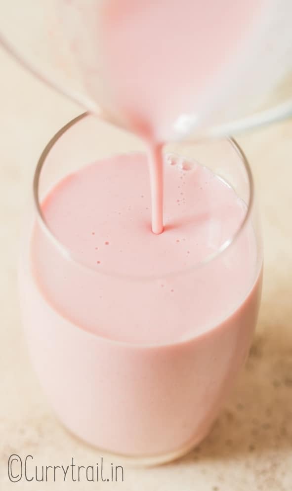 pouring strawberry milk into a glass
